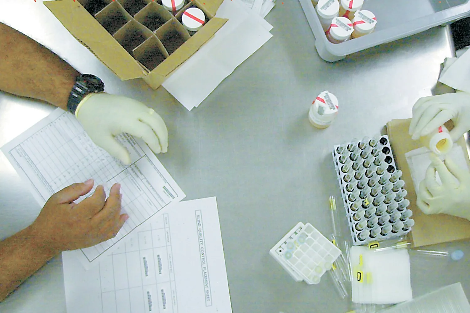 Laboratoriotyöntekijät täyttävät lomaketta näytteiden vieressä